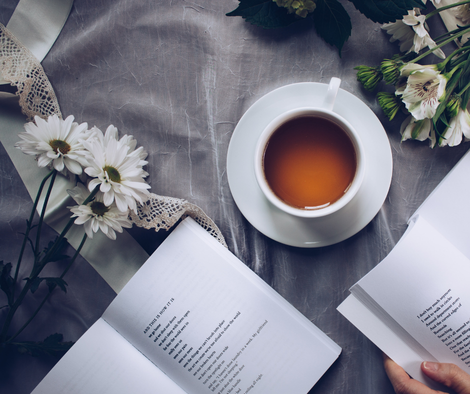A light gray background with a cup of coffee in the middle, white flowers on the right and left sides, and two poetry books that are open on the bottom of the image. There is a hand next to one of the books. Lace and ribbon run across the image as well.